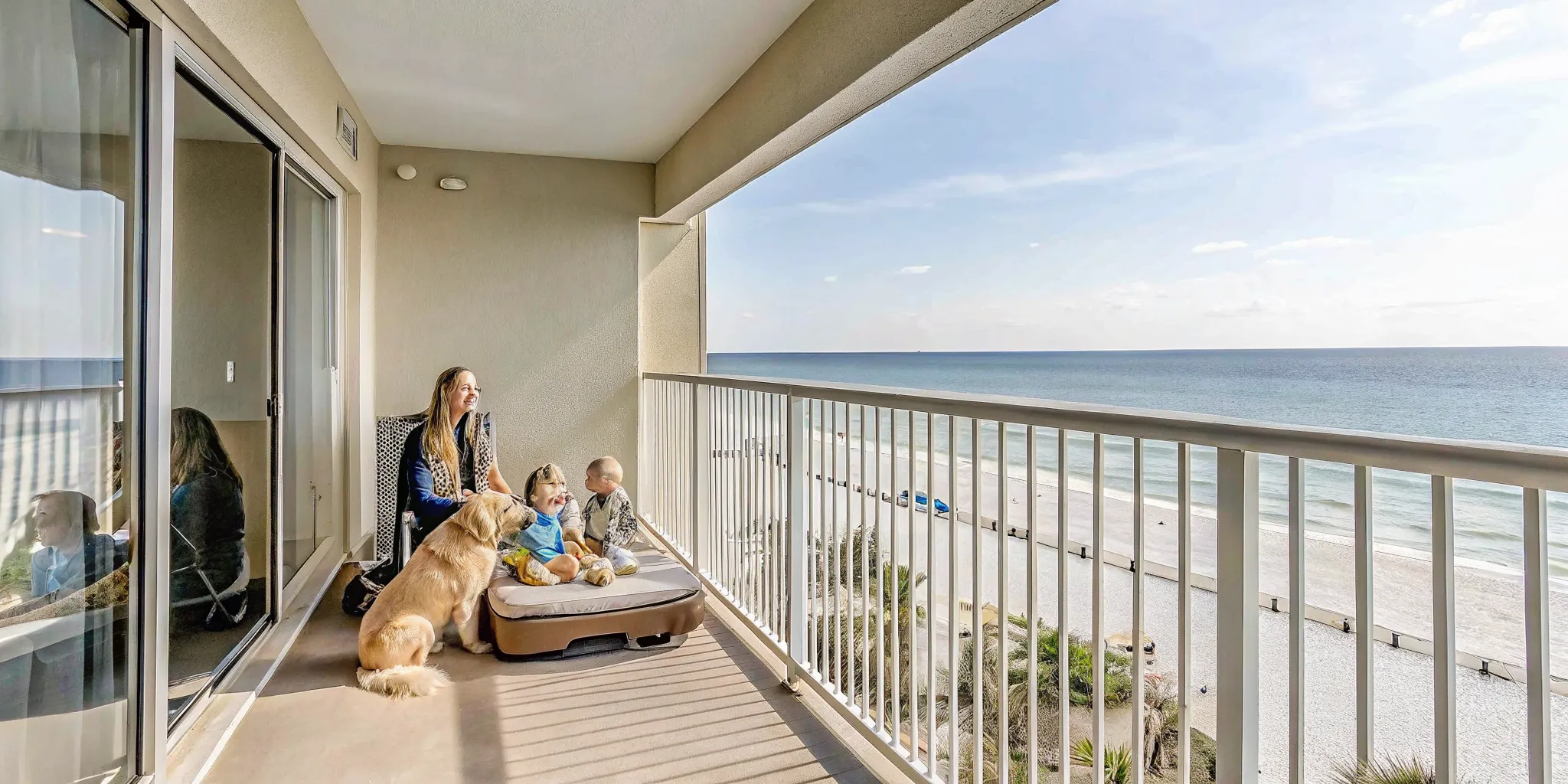 Family with a golden retriever on a Panama City Beach balcony overlooking the Gulf of Mexico at a luxury pet-friendly vacation rental