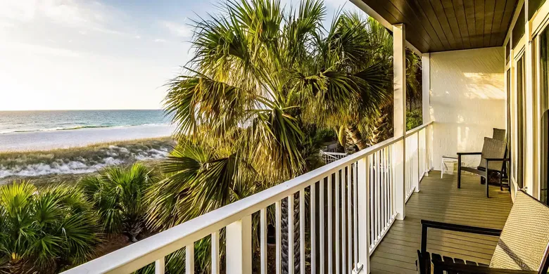 Stunning luxury beach house balcony overlooking a quiet white sand beach in Panama City Beach during a warm autumn sunset