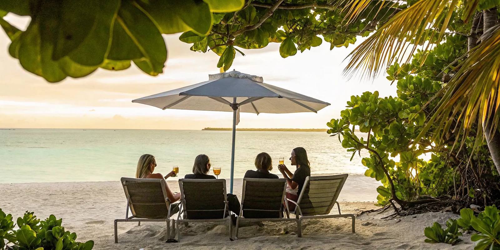 Four women relaxing together on the Panama City Beach shoreline at golden hour