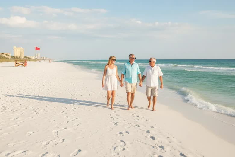 First-time visitors walking along the shoreline at Panama City Beach on a bright day