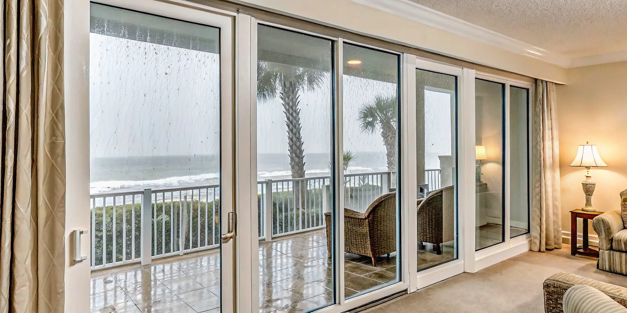 Cozy luxury vacation condo interior with view of palm trees in tropical rain