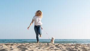 A woman with her dog on the beach, one of the best things to do when staying at pet-friendly rentals in Panama City Beach.